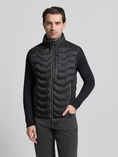 Männermodel trägt Regular Fit Steppweste mit Kapuze im Kragen von Tom Tailor, unifarben, Stehkragen, Reißverschluss, Ganzkörperansicht von vorne.