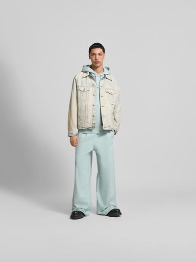Männermodel trägt Wide Fit Sweatpants mit elastischem Bund von MM6 Maison Margiela aus reiner Baumwolle, hellblau, Ganzkörperansicht von vorne.