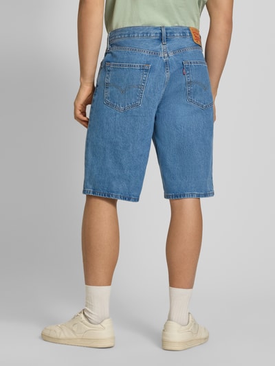 Männermodel trägt Loose Fit Jeansshorts aus reiner Baumwolle Modell '469' von Levi's®, blaue Denim-Optik, Label-Patch, 5-Pocket-Design, Ganzkörperansicht Rückansicht.