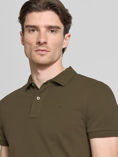 Männermodel trägt Slim Fit Poloshirt mit Logo-Stitching von Geox in Olivgrün, Strukturmuster, reine Baumwolle, Nahaufnahme Oberkörper.