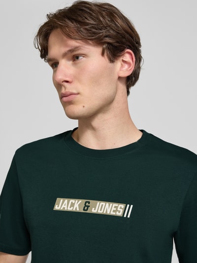 Mannenmodel draagt Regular Fit T-shirt met logoprint model 'Munk' van JACK & JONES, puur katoen, ruglengte maat M 74 cm, Nahaufnahme bovenlichaam.