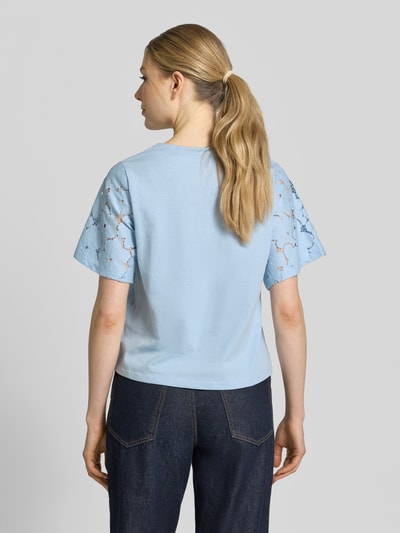 Frauenmodel trägt Regular Fit Blusenshirt aus reiner Baumwolle Modell 'VILLA' von Vero Moda, hellblau, Spitzenbesatz, unifarben, Ganzkörperansicht Rückansicht.