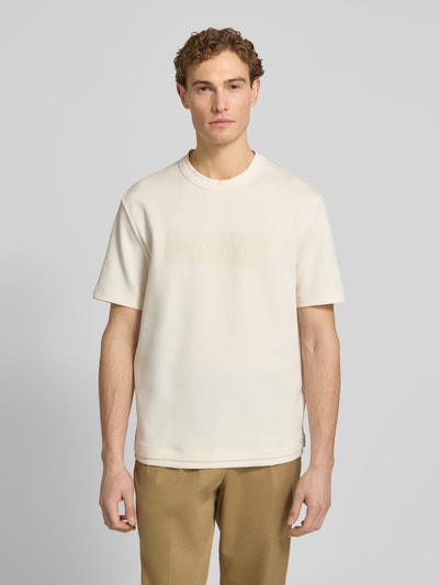 Männermodel trägt T-Shirt mit Logo und Rundhalsausschnitt von ARMANI EXCHANGE in Beige, Reine Baumwolle, Regular-Fit, Ganzkörperansicht von vorne. Rückenlänge bei Größe M: 71 cm.