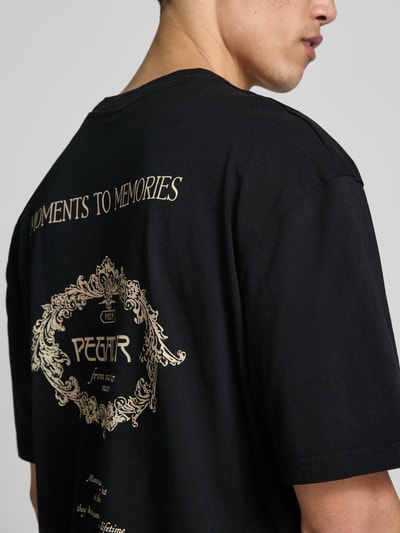 Männermodel trägt Oversized T-Shirt mit rückseitigem Motiv-Print Modell 'Reine' von Pegador in Schwarz und Reine Baumwolle, Nahaufnahme Rückseite.