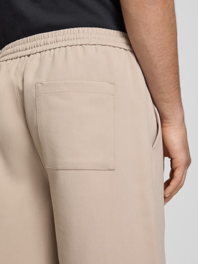 Männermodel trägt Loose Fit Shorts mit elastischem Bund Modell 'WILL' von Only & Sons, beige, Bundfalte, Gesäß- und Eingrifftaschen, Nahaufnahme Rückansicht.