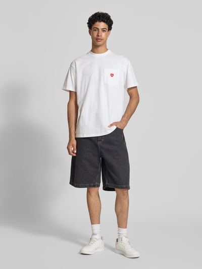 Männermodel trägt T-Shirt mit Brusttasche und Label-Patch von Carhartt Work In Progress, reine Baumwolle, Rundhalsausschnitt, Ganzkörperansicht von vorne.