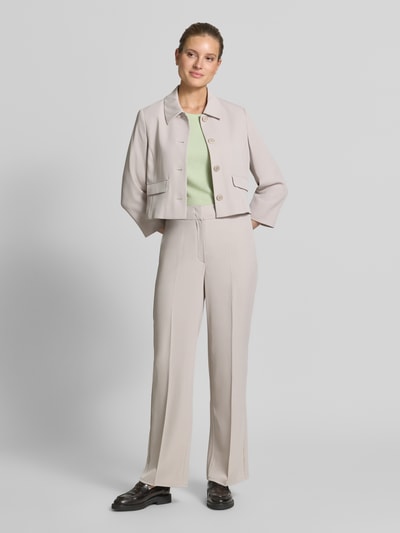 Modelka kobieca ma na sobie Regular Fit Blazer mit Umlegekragen od Betty Barclay w jasnym beżu, krój regular fit, elastyczna mieszanka materiałów, zielony top pod spodem, proste spodnie, produkt o długości pleców 49 cm, szerokość w rozmiarze 36: 47 cm, długość rękawa 52 cm, widok całej sylwetki z przodu.