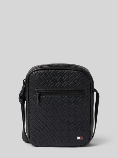 Produktfoto, Umhängetasche mit Logo-Detail Modell 'EMBOSSED FLAG' von Tommy Hilfiger in schwarzer Lederoptik mit Flag-Monogramm, Kunstleder, Reißverschluss, Schulterriemen, strukturiertes Muster, Hauptfach, Netz- und Reißverschlussfach, neutrale graue Hintergrundfarbe.