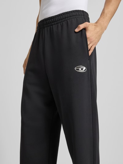 Männermodel trägt schwarze Sweatpants mit Label-Detail von Diesel aus reiner Baumwolle, lockerer Schnitt, gerader Bund, Nahaufnahme Oberkörper.