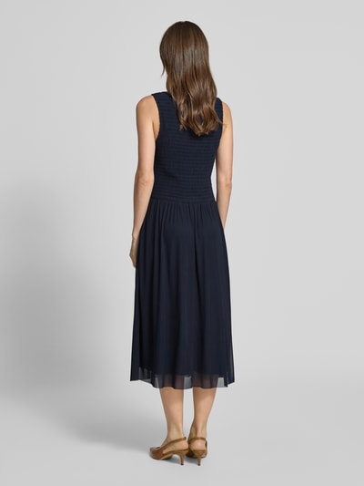 Frauenmodel trägt Midikleid aus Mesh mit Smok-Details von Christian Berg Woman Selection in Dunkelblau, gerade geschnitten, Ganzkörperansicht Rückansicht.