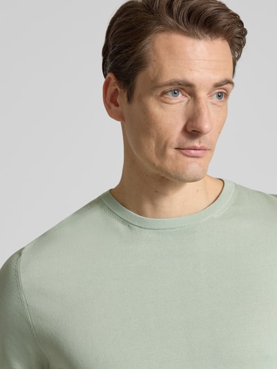 Männermodel trägt Regular Fit Strick-Shirt aus Bio-Baumwolle Modell 'TORINO' von Selected Homme, Look: effen, fijngebreid, korte mouw, ronde hals, Nahaufnahme Oberkörper.