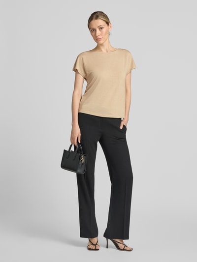 Frauenmodel trägt Relaxed Fit T-Shirt aus Viskose-Mix von COMMA in Beige mit Glitzer-Optik, U-Boot-Ausschnitt, schwarze Hose, Ganzkörperansicht von vorne.