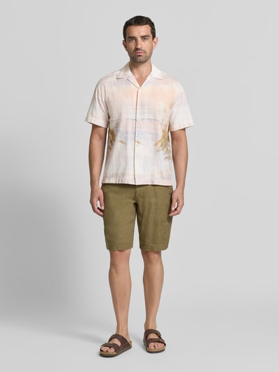 Männermodel trägt Regular Fit Freizeithemd aus reiner Baumwolle Modell 'SLHREGKELSO' von Selected Homme in Beige mit grüner Shorts, Ganzkörperansicht von vorne. Herren Freizeithemd von Selected Homme.