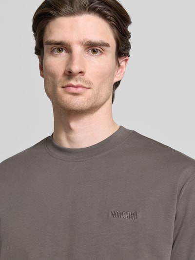 Mężczyznamodel nosi Regular Fit T-Shirt aus reiner Baumwolle Modell 'Baine' von WOODBIRD w kolorze szarym, okrągły dekolt, label-stitching, długość tyłu w rozmiarze M: 72 cm, zbliżenie na górną część ciała.