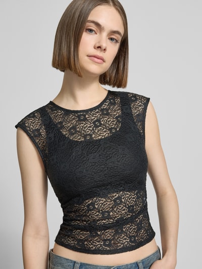 Frauenmodel trägt T-Shirt aus Spitze mit Raffung an der Seitennaht von REVIEW, schwarze Spitze, Elastischer-Material-Mix, Körpernahe Passform, Rundhalsausschnitt, Rückenlänge bei Größe S 45 cm, Nahaufnahme Oberkörper.