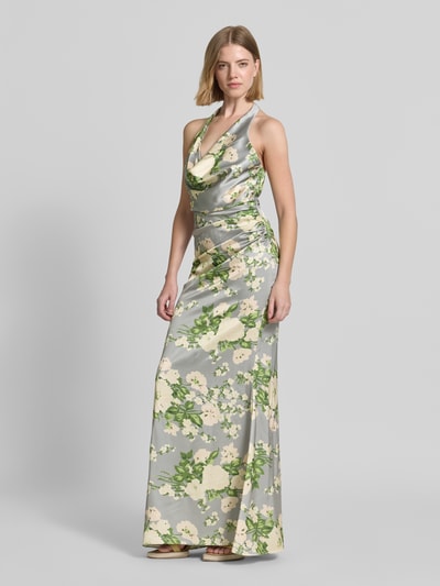 Frauenmodel trägt Abendkleid mit floralem Allover-Print von Mascara aus Satin, Taillierte Passform, Raffung, Neckholder, Rückenausschnitt, Blumen in Gelb und Grün auf grauem Untergrund, Glanzstruktur, Rückenlänge bei Größe 36: 160 cm, Brustweite bei Größe 36: 40 cm, Ganzkörperansicht von vorne.