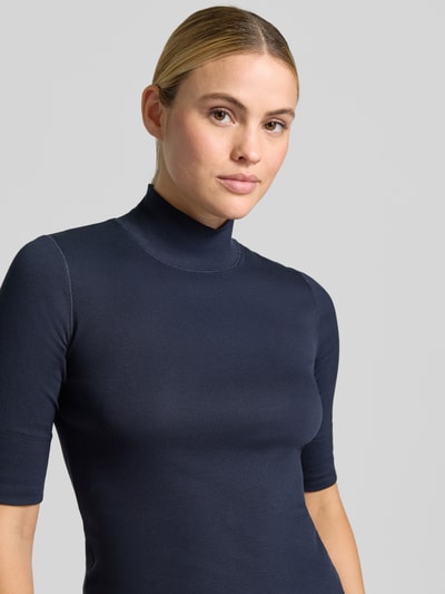Frauenmodel trägt Slim Fit Longsleeve aus Baumwoll-Mix von Marc Cain in Dunkelblau mit Stehkragen und halbem Arm, Nahaufnahme Oberkörper. Rückenlänge bei Größe 36: 58 cm, elastischer Stoff.