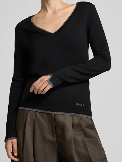 Frauenmodel trägt Slim Fit Longsleeve aus reine Viskose Modell 'Maglia Chiusa' von Liu Jo White in Schwarz mit V-Ausschnitt, Logo-Detail, Nahaufnahme Oberkörper.