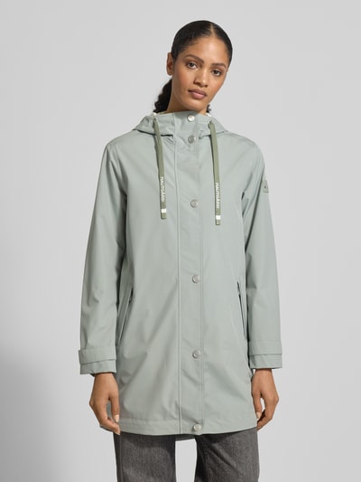 Frauenmodel trägt Jacke mit Ärmelriegeln von NAUTGÅRD in hellem Grau, Regular Fit, Kapuze mit Tunnelzug, Knopfleiste, Reißverschlusstaschen, glatte Oberfläche, Ganzkörperansicht von vorne.