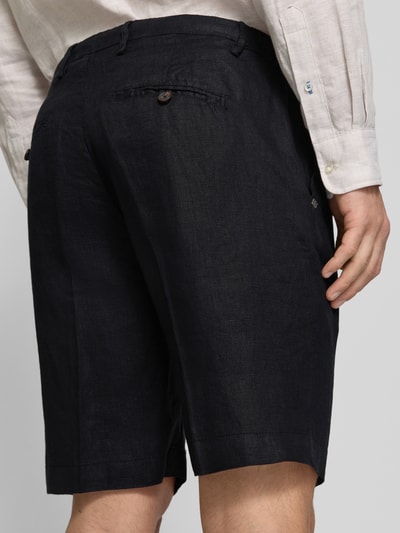 Männermodel trägt czarne szorty z lnu z wpuszczanymi kieszeniami Shorts aus Leinen mit Eingrifftaschen von MARKUP, krój straight fit, długość wewnętrzna nogawki 34 cm, szerokość w rozmiarze 50: 22 cm, kieszenie z tyłu z wypustką i zapięciem na guzik, zapięcie na guzik i zamek błyskawiczny, wpuszczane kieszenie boczne, widok tylni na całe ciało.