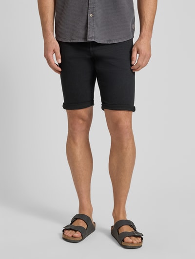Mannenmodel draagt Regular Fit Jeans Bermudas uit katoenmix van Tom Tailor in donkere denimlook, 5-pocket-design, knoopsluiting, regular fit, slim leg, label patch, riemlussen, detailopname van voren.