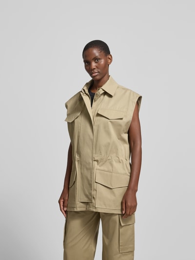 Frauenmodel trägt Weste aus reiner Baumwolle von Iro in Beige mit Umlegekragen, Pattentaschen, gerader Passform, Reißverschluss, Ganzkörperansicht von vorne.