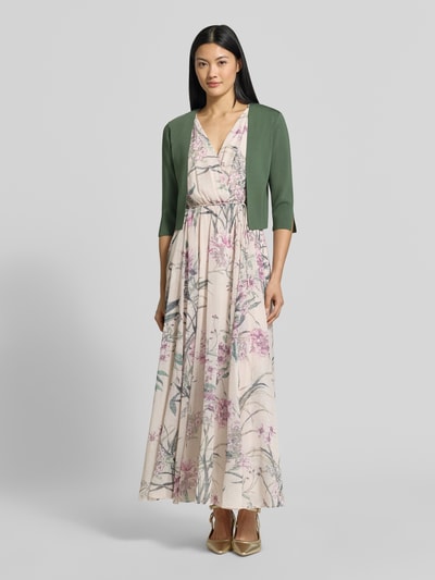 Frauenmodel trägt Regular Fit Bolero aus Viskose-Mix von Vera Mont in Grün über einem geblümten Kleid, Ganzkörperansicht von vorne. Damen Bolero von Vera Mont.