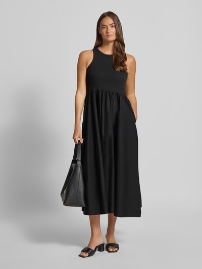 Frauenmodel trägt Midikleid mit Rundhalsausschnitt Modell 'MIRI' von YAS, Baumwoll-Elasthan-Mix, A-Linie, schwarze Farbfläche, Ganzkörperansicht von vorne. Rückenlänge bei Größe S: 125 cm, Brustweite bei Größe S: 37 cm.