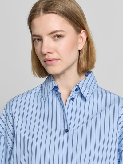 Frauenmodel trägt Oversized Hemdbluse aus reiner Baumwolle Modell 'BOSTATTA' von BOSS Orange mit Allover-Muster Gestreift, Hemdkragen, Label-Stitching-Applikation, Knopfleiste, Langarm und Manschette, Nahaufnahme Oberkörper.