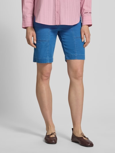 Frauenmodel trägt Straight Fit Shorts mit Gesäßtaschen Modell 'Sue' von TONI aus Elastischer-Baumwoll-Mix, leuchtend blau, Nahaufnahme Oberschenkel bis Schuhe.