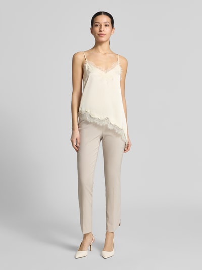 Vrouwenmodel draagt Hose aus Viskose-Mix mit elastischem Bund Modell 'Ina' van STEHMANN in beige, verkorte fit, gladde textuur, vooraanzicht hele lichaam, context: viscosemix met stretch, elastische taille, maat 36: taillewijdte 37 cm, binnenbeenlengte 93 cm.