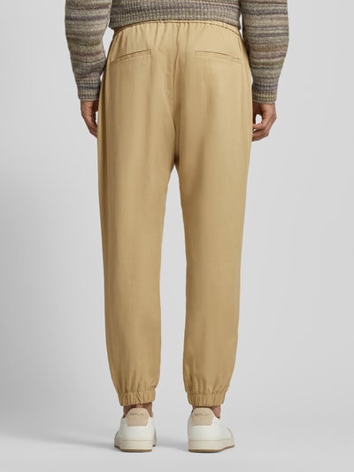 Männermodel trägt Loose Fit Stoffhose aus Lyocell-Leinen-Mix von Antony Morato in Beige mit elastischem Bund, Gesäßtaschen, Ganzkörperansicht Rückansicht.
