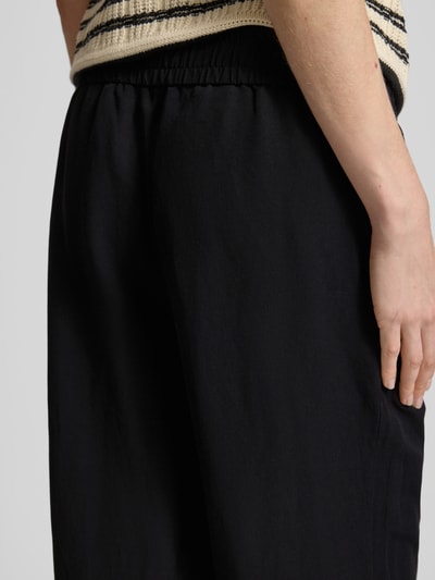 Vrouwenmodel draagt Leinenhose mit elastischem Bund Modell 'Roma' van STEHMANN, zwart, wide leg, puur linnen, detailopname heup.