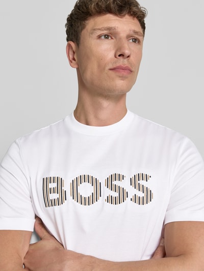 Mężczyzna nosi Regular Fit T-Shirt aus reiner Baumwolle Modell 'C-THOMPSON 41' von BOSS, biały, jednolity, krótki rękaw, okrągły dekolt, merceryzowana bawełna, aplikacja z logo na piersi, zbliżenie na górną część ciała