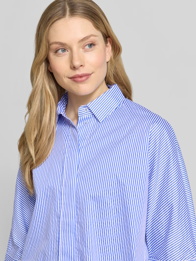 Frauenmodel trägt Regular Fit Hemdbluse mit durchgängiger Knopfleiste von Christian Berg Woman, reine Baumwolle, Hemdblusenkragen, Halbarm, blau-weiß gestreift, glatte Textur, Nahaufnahme Oberkörper.