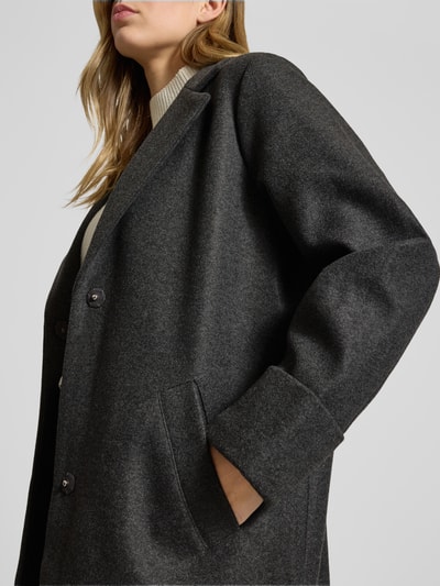 Frauenmodel trägt Mantel mit Reverskragen Modell 'CADDY' von Noisy May, Relaxed-Fit, Eingrifftaschen, Ärmel mit Aufschlag, Nahaufnahme Oberkörper.