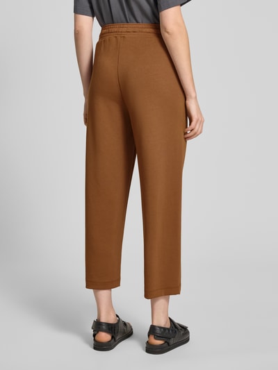 Kobiece modelka nosi spodnie dresowe Wide Fit Sweatpants in verkürzter Passform Modell 'Banu' von Soyaconcept, elastyczna mieszanka materiałów z domieszką modalu, kolor brązowy, skrócony krój, pas z tunelem; pełny widok z tyłu.