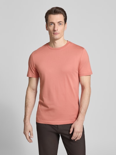 Männermodel trägt T-Shirt mit Rundhalsausschnitt von Christian Berg Men in Koralle, glatte Struktur, Regular Fit, Ganzkörperansicht von vorne.