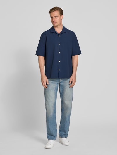 Männermodel trägt Relaxed Fit Freizeithemd aus Seersucker-Material von Tommy Hilfiger, Farbe Dunkelblau, Ganzkörperansicht von vorne.