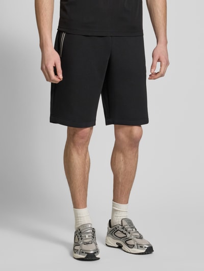 Männermodel trägt schwarze Shorts mit elastischem Bund von EA7 Emporio Armani, Material-Mix, Regular Fit, Ganzkörperansicht von vorne.