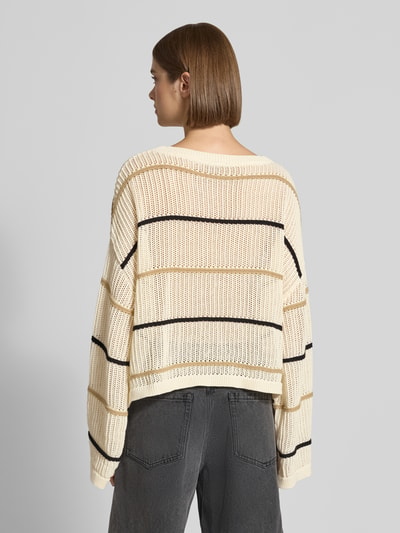 Frauenmodel trägt Oversized Strickpullover mit Label-Detail und Rundhalsausschnitt von Karo Kauer, grober cremefarbener Strick mit schwarzem Streifenmuster, Rückenlänge bei Größe S 55 cm, Ärmellänge 76 cm, Ganzkörperansicht Rückansicht.
