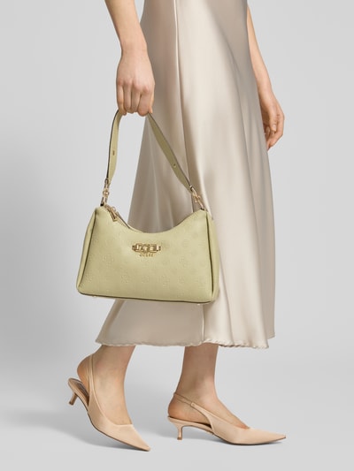 Frauenmodel trägt Shoulder Bag in Leder-Optik mit Logo-Detail Modell 'Anise' von Guess, Hauptfach mit Reißverschluss, Schulterriemen, cremefarbene Töne, glatte und strukturierte Oberfläche, Abmessungen 30 cm Breite, 19 cm Länge, 8 cm Tiefe, Riemenlänge 52 cm, Ganzkörperansicht von vorne.