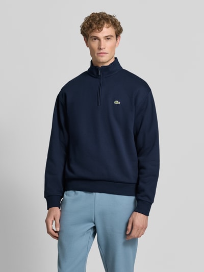 Männermodel trägt Regular Fit Troyer aus Baumwoll-Mix von Lacoste in Dunkelblau, weiche Textur, Ganzkörperansicht von vorne, Herren Troyer von Lacoste