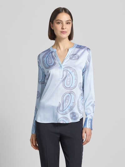 Frauenmodel trägt Regular Fit Bluse aus Seiden-Mix von HERZENS in Hellblau mit Allover-Paisley-Print, Tunika-Ausschnitt, langärmelig, Ganzkörperansicht von vorne. Rückenlänge bei Größe 36: 68 cm, Ärmellänge: 62 cm, elastischer Seiden-Mix.