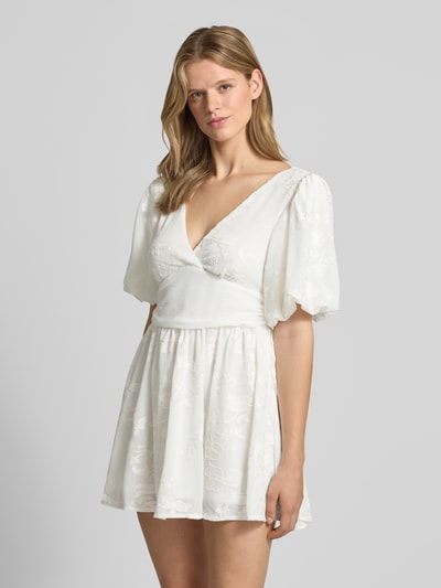 Frauenmodel trägt Minikleid mit Ballonärmeln von Gina Tricot in Weiß, taillierter Schnitt, V-Ausschnitt, Embroidery Design, Nahaufnahme Oberkörper.