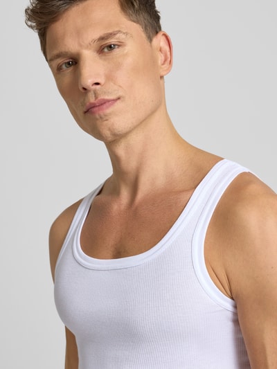 Mannelijk model draagt Tanktop in Ripp-Optik van Götzburg Wäsche in wit, slim fit, ronde hals, katoenen ribstructuur. Nahaufnahme bovenlichaam.