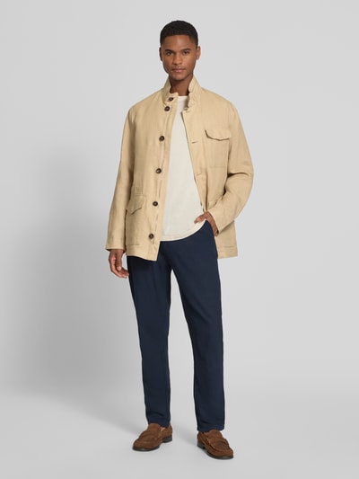 Męski model nosi Leinenjacke mit Stehkragen und Pattentaschen od bugatti, beż, czysta len, krój regular fit, długość tyłu w rozmiarze 50: 74 cm, szerokość ramion w rozmiarze 50: 46 cm, szerokość klatki piersiowej w rozmiarze 50: 55 cm, długość rękawa w rozmiarze 50: 64 cm, widok całej sylwetki z przodu.