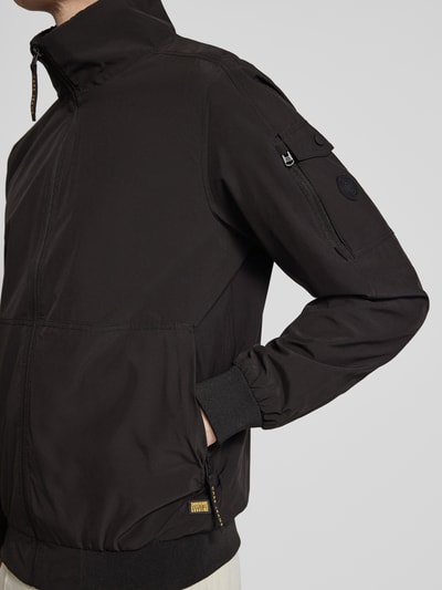 Männermodel trägt schwarzen Windbreaker mit Stehkragen Modell 'YETUR' von CARS JEANS, Reißverschlusstasche am Arm, Nahaufnahme Oberkörper.