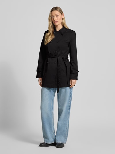 Frauenmodel trägt Regular Fit Trenchcoat mit Taillengürtel zum Binden Modell 'CHALSEA OLIVIA' von Vero Moda, Optik: Unifarben in Schwarz, Passform: Regular-Fit, Kragenform: Umlegekragen, Verschluss: doppelreihige Knopfleiste, Details: Nähte, Ärmelform: Langarm mit Riegel, Taschen: seitliche Eingrifftaschen, Materialverarbeitung: Twill, Ganzkörperansicht von vorne.