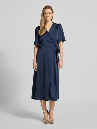 Frauenmodel trägt Midikleid in Wickel-Optik Modell 'VIENNA RAVENNA' von Vila aus dunkelblauem Satin, taillierter Schnitt, V-Ausschnitt, Ganzkörperansicht von vorne. Rückenlänge bei Größe 36: 125 cm, Brustweite 50 cm, Ärmellänge 30 cm.